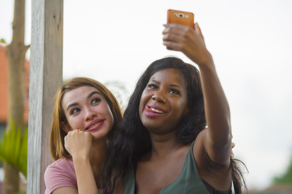 African woman taking funny selfie with friend.